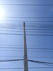 electricity post with blue sky and sun, power lines and wires