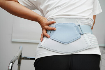 Asian woman wearing lumbar support pain back and use walker in hospital.