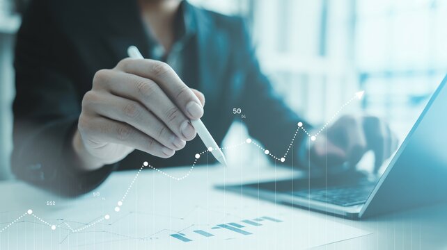Confident professional analyzes financial growth charts with stylus on laptop, visualizing successful business strategy and market trends.