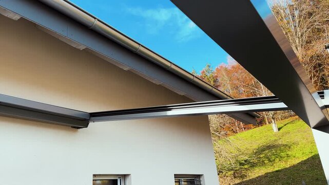 A sleek electric pergola installed on a house, providing adjustable sun protection and enhancing outdoor living space and home value.