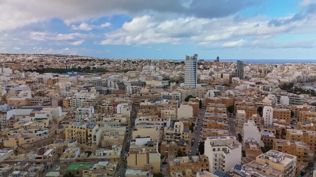Drone aerial view of the densely built urban area of Msida, Gżira, Sliema, and San Ġwann in Malta, showcasing mixed architecture, modern towers, and Mediterranean coastal skyline.