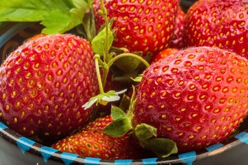Close up of fresh ripe strawberries in a bowl with green leaves