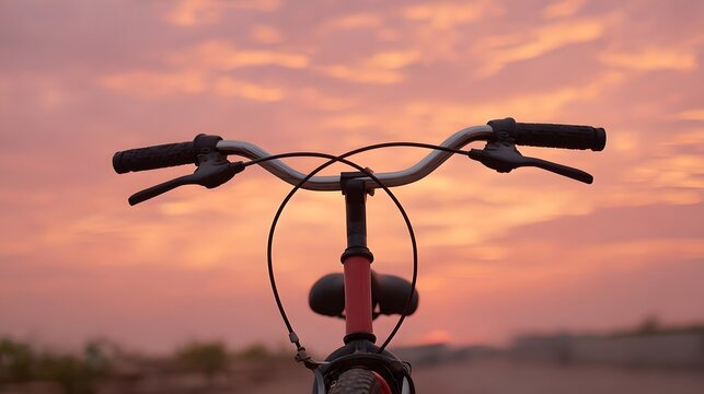 Bicycle handlebars against a vibrant pink and orange sunset