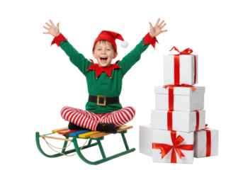 Young caucasian boy in elf costume, joyfully raising arms on colorful sled, next to white gift boxes, against transparent background, Christmas excitement and holiday celebration