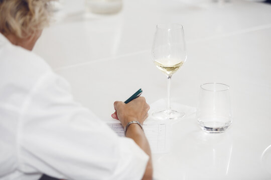 Close up faceless shot of female sommelier tasting white wine during lecture for novice wine experts. Sommelier school, winemaking master class. 