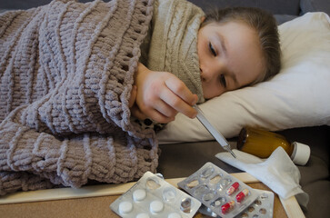 A little girl is lying in bed sick. 
The concept of illness, cold, acute respiratory viral infection