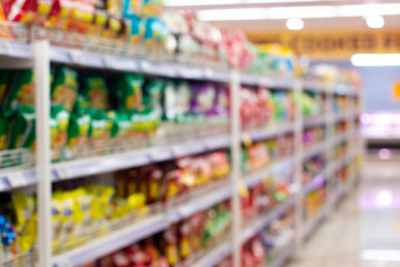 Blurred view of supermarket aisles filled with colorful snack products.