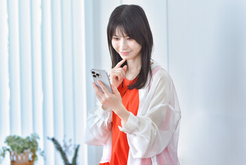 部屋でスマホを見る若い女性