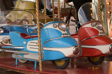 Colorful retro carousel featuring miniature cars at a bustling city fair in autumn evening light © kinovo