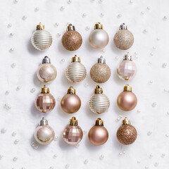 Collection of Christmas baubles small balls in beige gold tones, flat lay on white fur. Festive holiday decoration with glitter, minimal style. Xmas Seasonal design, greeting cards, new year photo