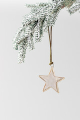 Christmas bauble shiny golden star hanging on green Christmas fir branch. Festive holiday chrome metallic decoration, minimal style. Xmas greeting cards, new year aesthetic background, copyspace