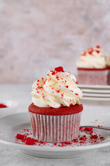 Red velvet cupcakes with cream cheese frosting and red sugar hearts. Delicious dessert for Valentines day. Selective focus, copy space.