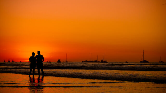 Silhouette of a couple looking at sunset on a tropical beach - Powered by Adobe
