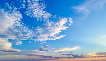 A breathtaking expanse of vibrant blue sky adorned with an array of dynamic white clouds, capturing the serene beauty of the atmospheric natural world at dawn or dusk