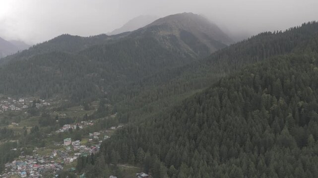 Pulga and Kalga villages in Parvati Valley, Himachal Pradesh, showing the lush green Fairy Forest with pine and deodar trees, snow-capped mountains, and clouds touching the peaks in autumn.