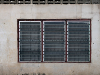 Old Weathered Concrete Wall with Three Glass Jalousie Louvre Windows and Metal Grilles