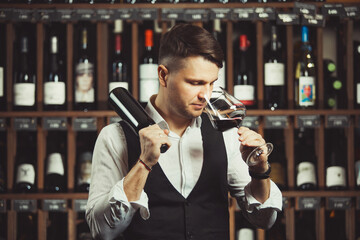 Bokal of red wine on background, male sommelier appreciating drink