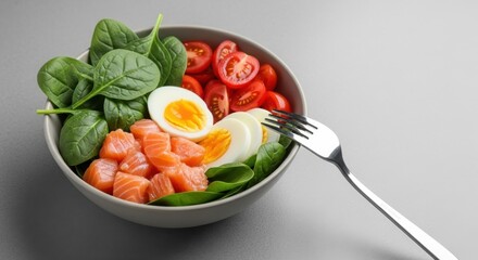 Healthy salmon and egg salad bowl made with spinach and tomatoes. Healthy food bowl