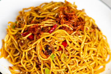 Close-up of homemade spicy asian fried noodles served on a white plate.