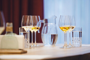 Elegant wine glasses with different white and sparkling wines on the table during the preparation for the tasting.