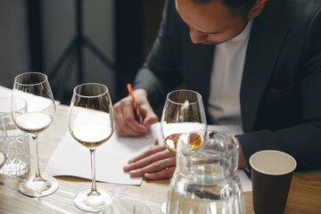 Sommelier makes notes on the tasting card. Wine blind tasting.
