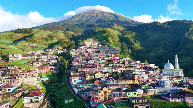 Scenic drone shot of a colorful mountain village known as Nepal van Java. Located on the slopes of Mount Sumbing, the landscape features terraced farms, vibrant houses, and breathtaking natural beauty