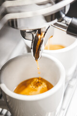 Close-up of Freshly Brewed Espresso With Rich Crema Being Poured Into White Cups From Holder