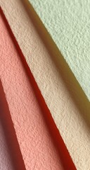 Close-up of four pastel-colored textured fabric swatches, diagonally arranged, showcasing subtle color variations and a slightly rough surface