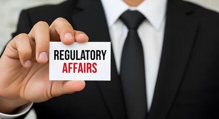 A businessman in a suit holds up a business card displaying the text "Regulatory Affairs".