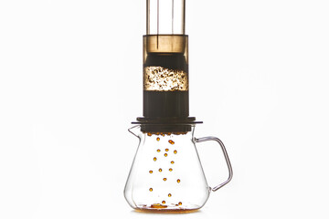 Brewing of Coffee by Creates Pressure Aeropress Method Where Drops Flow From Flask Into Glass Pot, Creating Rich and Fragrant Coffee Drink Against White Background with a Free Copy Space