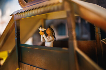 A delicate figurine of a girl holding a white dove, nestled within a miniature wooden structure....