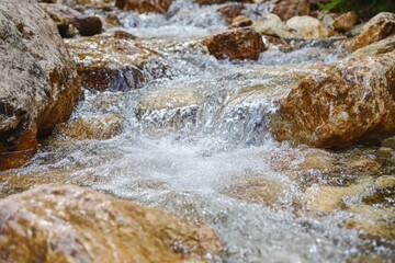 A serene stream meanders through a rocky landscape, its gentle flow creating a soothing melody.