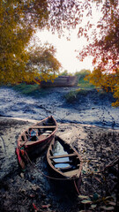 two wooden boats resting on low tide mudflat in the evening.