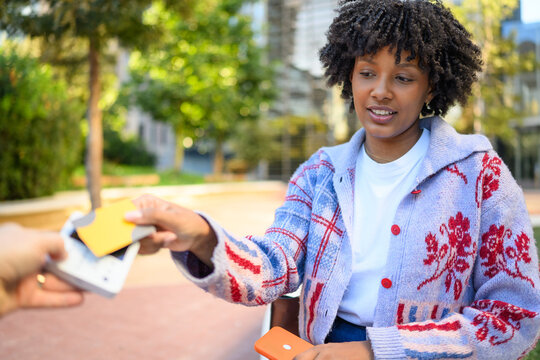 Smiling woman making contactless card payment outdoors