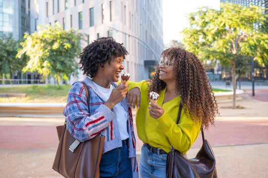 Happy women friends enjoying ice cream in city street - Powered by Adobe