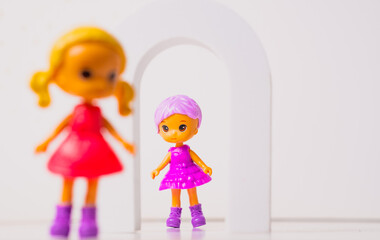 Colorful toy dolls playing together in a vibrant setting with feathers and an arch