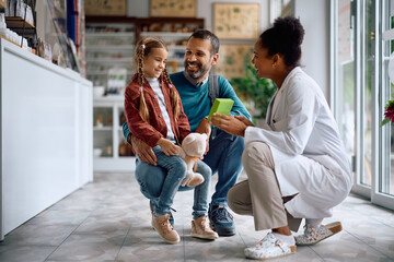 Happy father and daughter communicating with pharmacist while buying vitamins in a pharmacy.