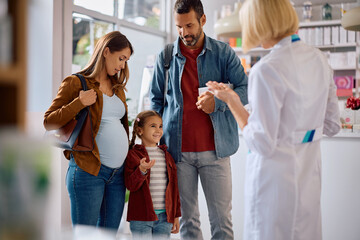 Happy family talking to a pharmacist in a pharmacy.