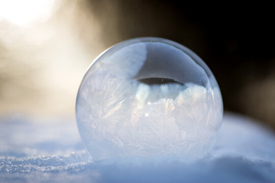 A frozen bubble in the snow. Beautiful frosty patterns on a frozen soap bubble. winter, frosty background. Frozen bubble. soap bubble on snow close up. winter season, cold time. macro photo