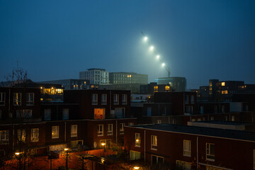 Tall crane with lights over houses in  twilight