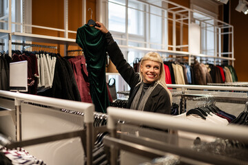 Woman shopping for green dress in clothing store