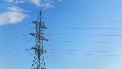 High Voltage Power Lines Stretching Against a Clear Blue Sky, Towering Above the Landscape
