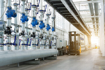 Large industrial water treatment and boiler room. Shiny steel metal pipes and blue pupms and valves.