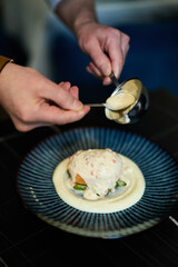 Chef pouring creamy sauce over salmon