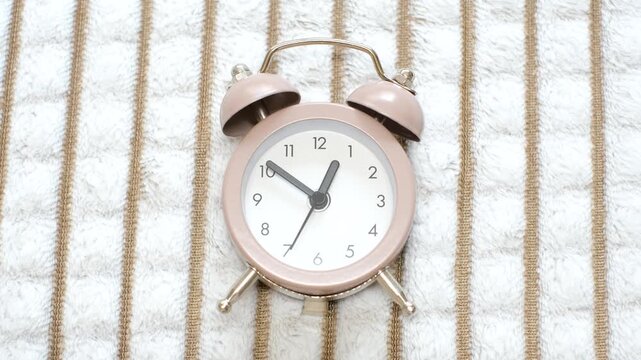 Brown alarm clock against the background of a crumpled plush blanket, top view close-up.