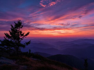 Fototapeta premium Majestic Mountain Sunset: Silhouette Tree, Vibrant Sky, Layered Peaks