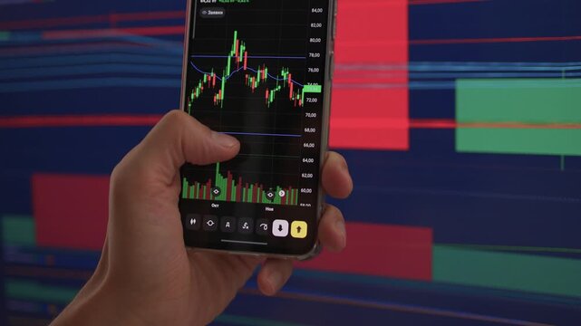 Trader observes price fluctuations closely, Hands manipulate trading charts intensely during session, Trader focuses on chart patterns and volume data to make informed choices