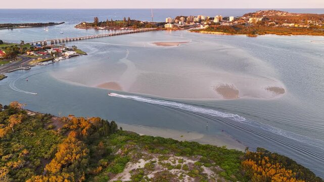 Dynamic aerial footage capturing boats cruising through the scenic channel between Forster and Tuncurry. Clear waters, gentle wake trails, and the iconic bridge in the background 