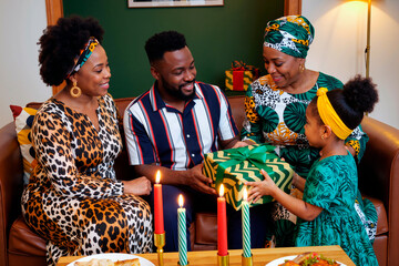 Black family gathering, young adult man smiling while receiving wrapped gift from Black girl, two middle aged Black women sitting nearby, celebrating together in living room
