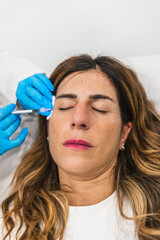 Woman lying down receiving cosmetic injection in her face for wrinkle reduction and beauty enhancement at a clinic